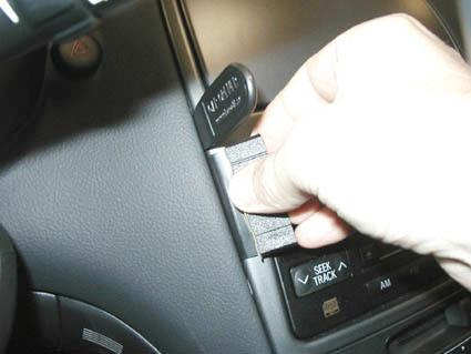 En hand som justerar en komponent på en bilpanel.