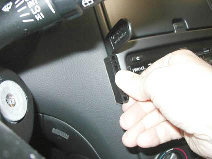 En hand som håller i en svart plastdel vid bilens rattsystem.