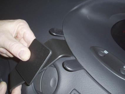 En hand som håller en svart del nära bilen instrumentpanel.