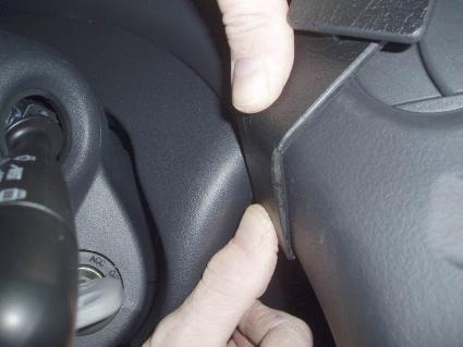 Visar en hand som justerar något vid ratten i en Toyota Yaris 03-05.