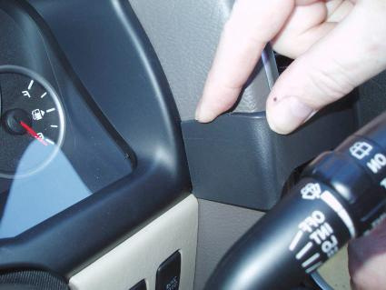 En hand pekar på en monteringsbygel i en bilinteriör.