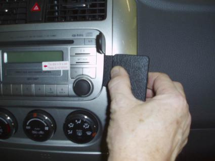 Hand håller i en svart del som verkar relatera till bilens instrumentbräda.