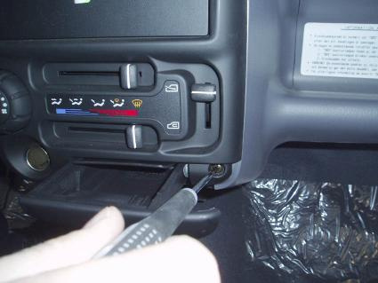 En hand som använder verktyg på bilens kontrollpanel.