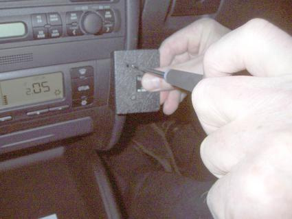 En hand som använder en penna på en bilpanel, troligen för installation eller justering.