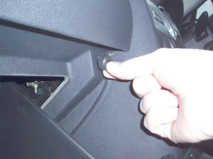 En hand trycker på en knapp i bilen, nära förarkonsolen.