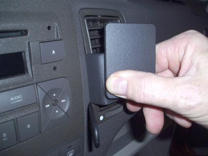 En hand sätter in en vinklad enhet i en bils ventilationsuttag.