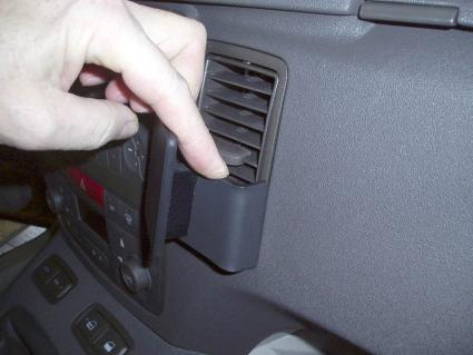 En hand monterar en vinklad hållare i en bils ventilationssystem.