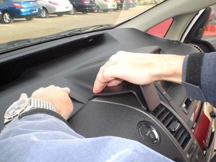 En hand monterar en del av instrumentpanelen i en Toyota Prius.