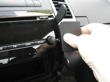 En hand placerar en svart platta på bilens instrumentpanel.