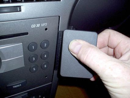 En hand öppnar en lucka på en bilstereo i en Opel Astra.