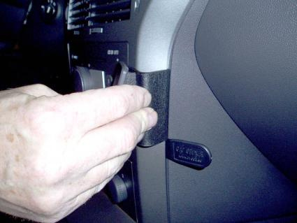 En hand installerar något på insidan av en bilpanel.