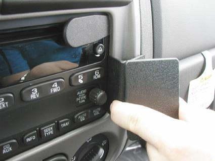 Bild på en bilstereo med fokus på kontroller och en hand som justerar.