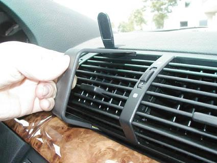 En hand håller en del som fästs på bilens luftventil.