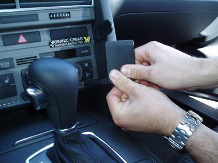 En hand håller en svart kortbit nära bilens instrumentpanel.