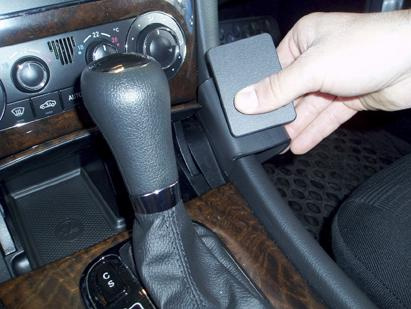 En hand håller en vinklad låg del nära växelhuset i en Mercedes Benz C-Klass.