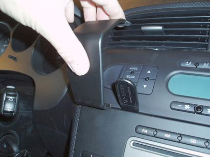 En hand som håller i en svart konsolbit vid bilens luftventil.