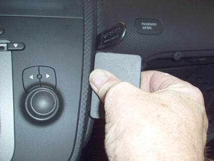 En hand som håller en grå spacer nära kontroller i en bil.