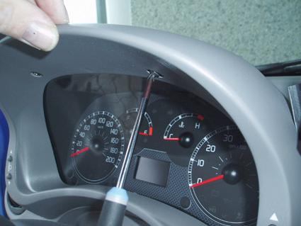 Bild visar en person som skruvar loss instrumentpanelen i en Fiat Panda.