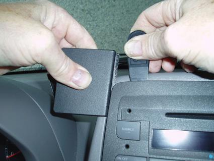 Två händer installerar en komponent i en Fiat Panda.