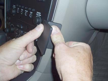 Händer som trycker på en knapp i bilens instrumentpanel.