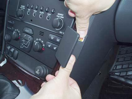 En person tar bort ett panelttle från instrumentbrädan i en Volvo V70.