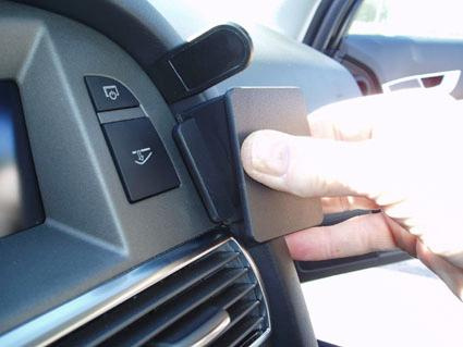 En hand som fäster en svart enhet på instrumentpanelen i en Audi A6.