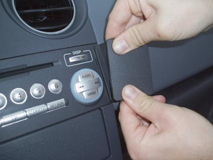 En hand tar bort en panel vid bilens ljudsystem.