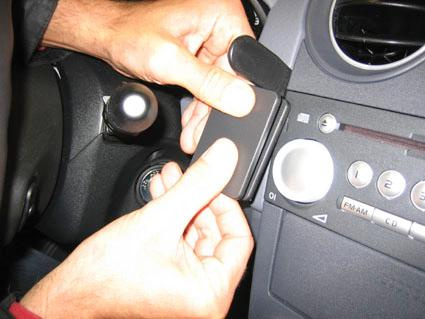 En person fäster en enhet på bilens instrumentpanel.