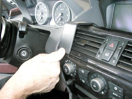 En hand placerar en monteringsbygel nära bilens instrumentpanel och luftventiler.