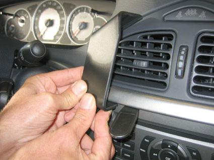 En hand håller i en del av bilens inredning nära luftventilerna.