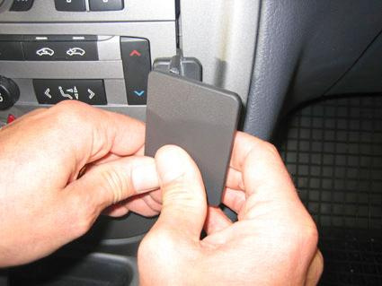 En person fäster en platta i bilens instrumentpanel.