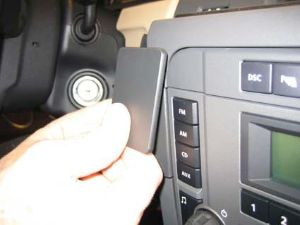 En hand håller en svart panel framför bilens instrumentbräda.