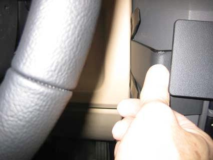 Bild visar en hand som trycker på en knapp eller spak i en bilinteriör.