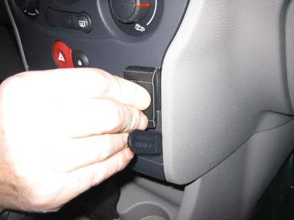 En hand som ansluter en enhet till instrumentpanelen i en Renault Modus.