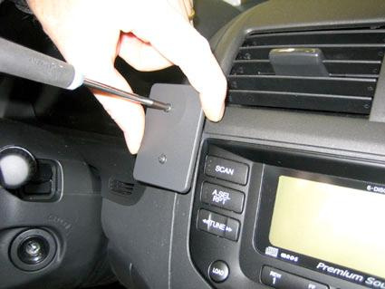 Bild visar en hand som håller en skruvmejsel mot en panel i en Honda Accord 03-07.