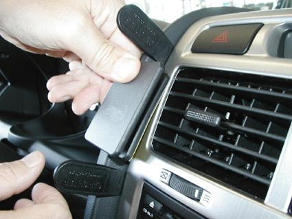 En hand håller i en del av bilens inredning, troligen en spänne eller hållare.