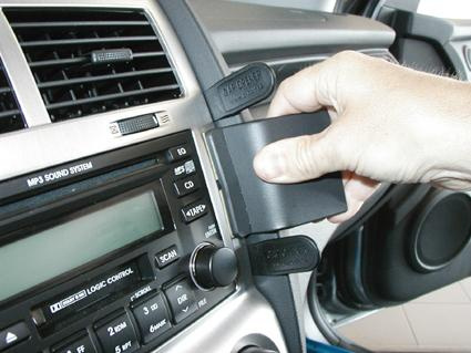 En hand installerar en Bluetooth-enhet i bilens instrumentpanel.