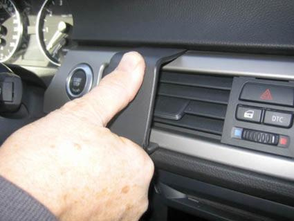 En hand som trycker på en del av bilens instrumentbräda.