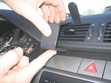 En hand installerar en del av luftventilationen i en Volkswagen Passat.