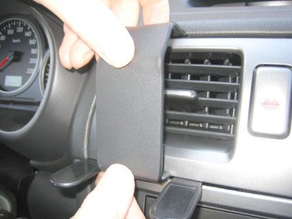 En hand som håller en svart del nära luftventil i en bil.