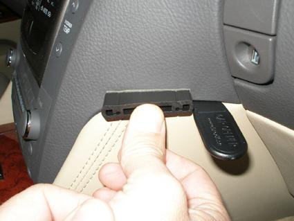 En hand håller en vinklad svart del av interiören i en Lexus GS.