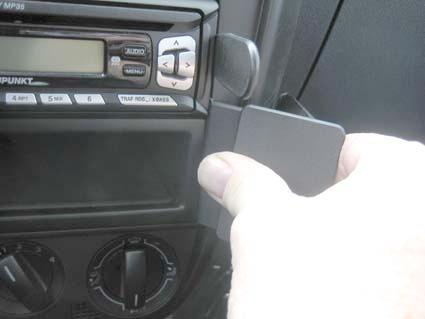 En hand som håller i en vinklad del av bilens inredning.