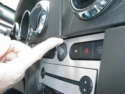 En hand trycker på en knapp i fordonsinredning.