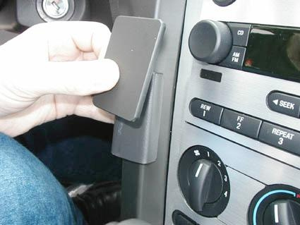 En hand placerar en enhet vid bilens centrumkontrollpanel.