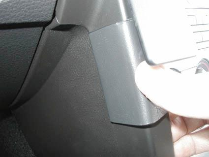 En hand som greppar ett svart plastdetalj i en bilinteriör.