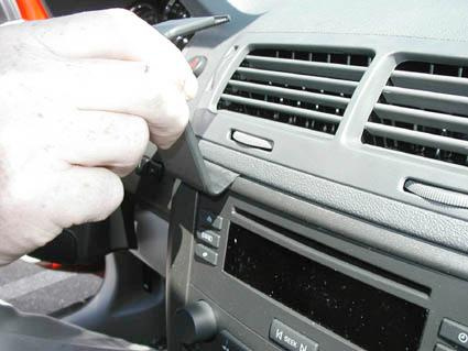 En hand justerar eller tar bort en del av bilens instrumentbräda.