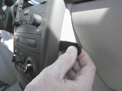 En hand som justerar en knapp i en bilinteriör.