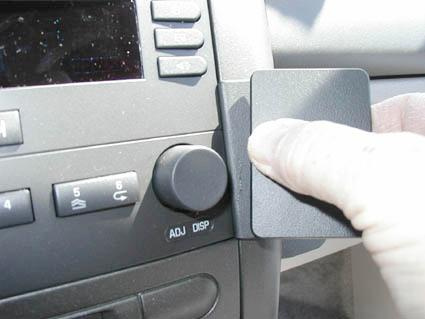 En hand som håller i en svart platta vid bilens instrumentpanel.