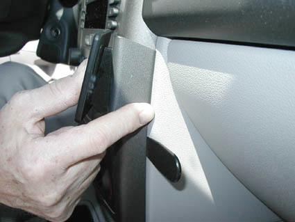 En hand trycker på ett panelparti i en bil.
