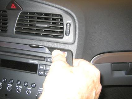 Hand som trycker på en knapp på en bilradion i Volvo V70.